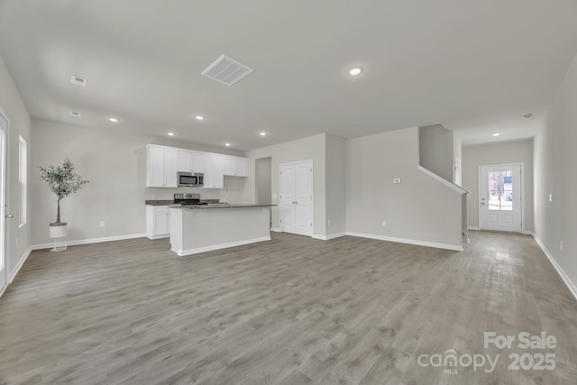 unfurnished living room with light wood-style floors, visible vents, baseboards, and recessed lighting