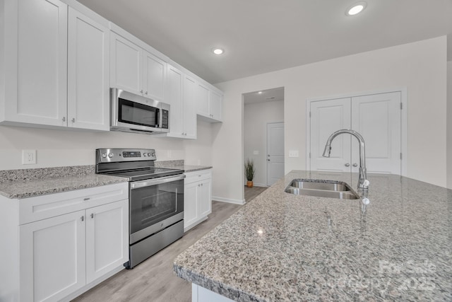 kitchen with appliances with stainless steel finishes, a sink, and white cabinetry