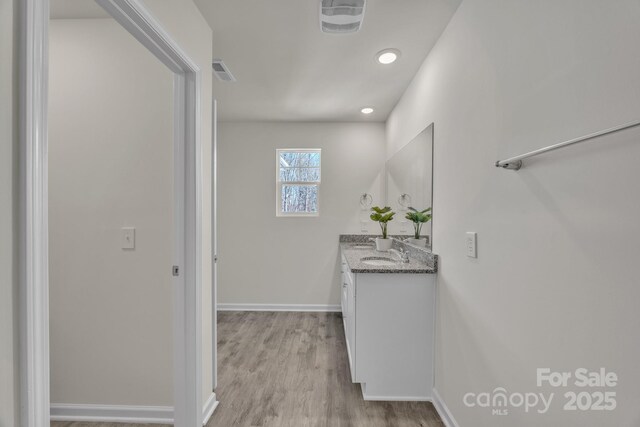 bathroom featuring baseboards, visible vents, wood finished floors, vanity, and recessed lighting