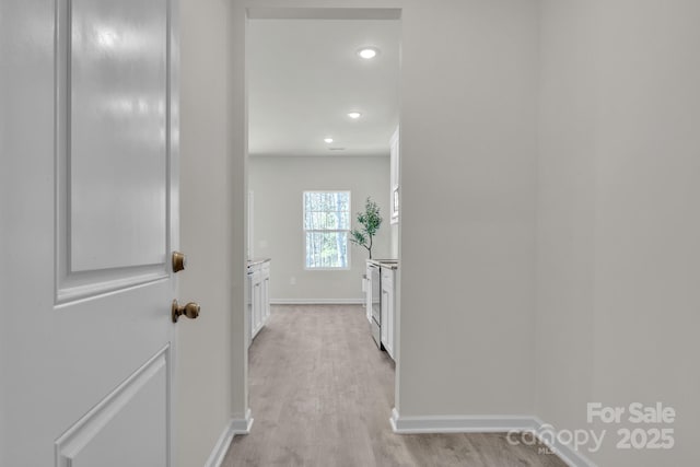 hallway featuring light wood-type flooring, baseboards, and recessed lighting