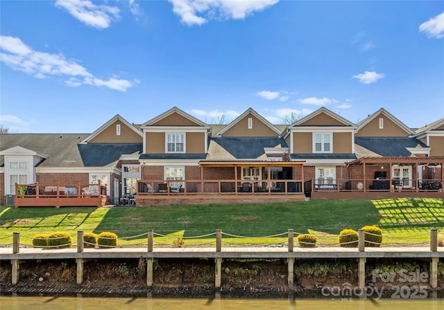 rear view of house featuring a water view and a lawn