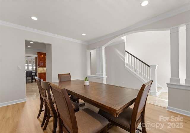 dining room featuring crown molding, light wood-type flooring, and ornate columns