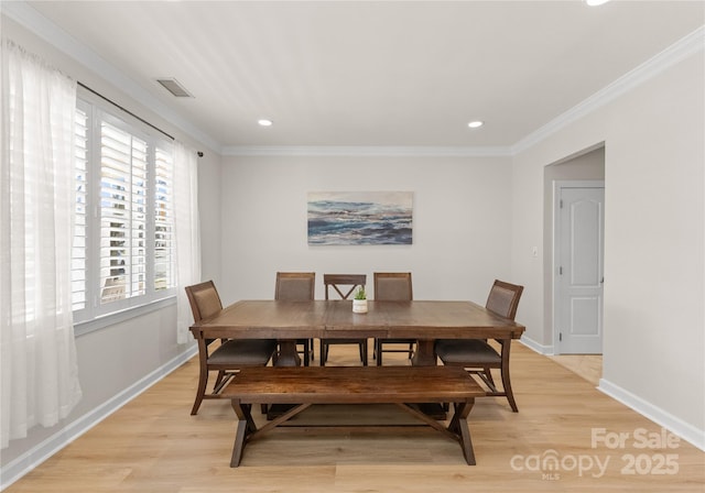 dining area featuring ornamental molding and light hardwood / wood-style flooring