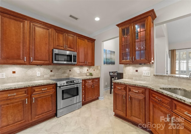 kitchen featuring stainless steel appliances, light stone counters, and decorative backsplash