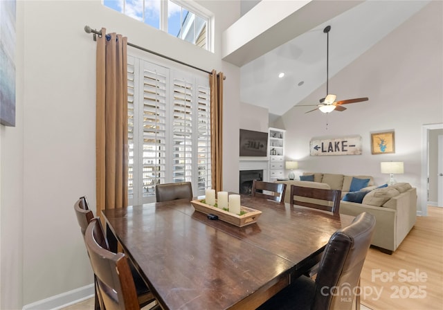 dining area featuring ceiling fan, high vaulted ceiling, and light hardwood / wood-style floors