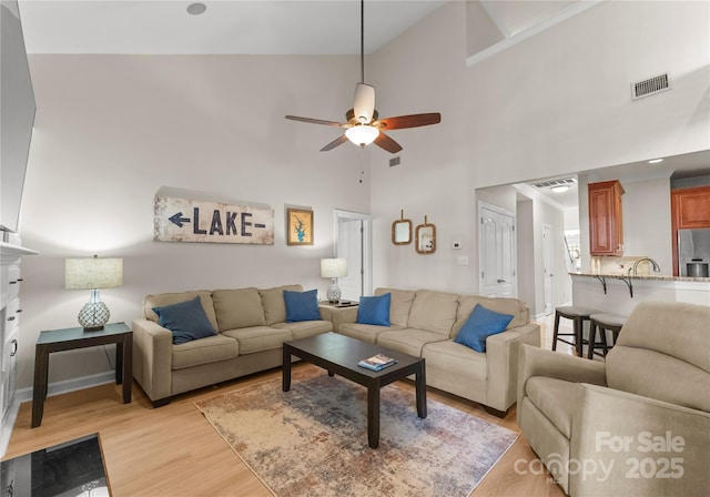 living room featuring sink, high vaulted ceiling, ceiling fan, and light wood-type flooring