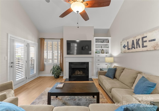 living room featuring light hardwood / wood-style flooring, vaulted ceiling, and ceiling fan