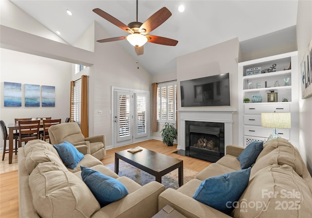 living room with ceiling fan, high vaulted ceiling, and light hardwood / wood-style floors