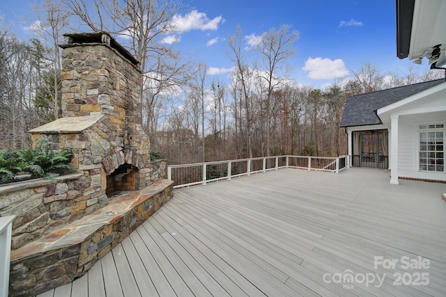 wooden terrace with an outdoor stone fireplace