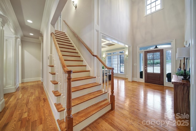 entryway with baseboards, light wood finished floors, and stairs