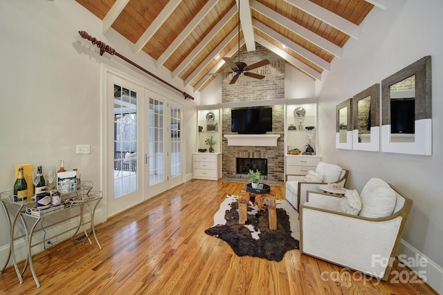 living room with beamed ceiling, a brick fireplace, wood finished floors, french doors, and wood ceiling