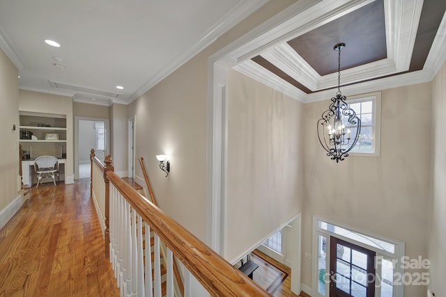 hallway featuring attic access, wood finished floors, an upstairs landing, and ornamental molding