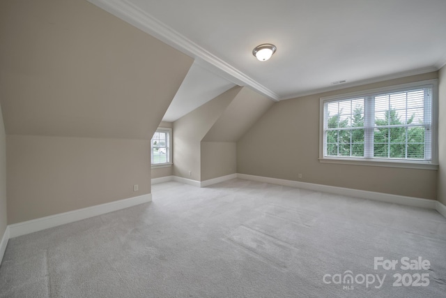 additional living space with baseboards, visible vents, vaulted ceiling, and light carpet