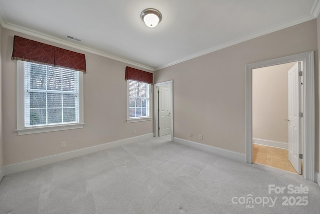 unfurnished bedroom with carpet flooring, ornamental molding, baseboards, and visible vents
