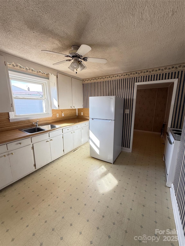 kitchen featuring sink, ceiling fan, a textured ceiling, white cabinets, and white fridge