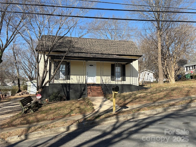 bungalow-style home featuring a porch and roof with shingles