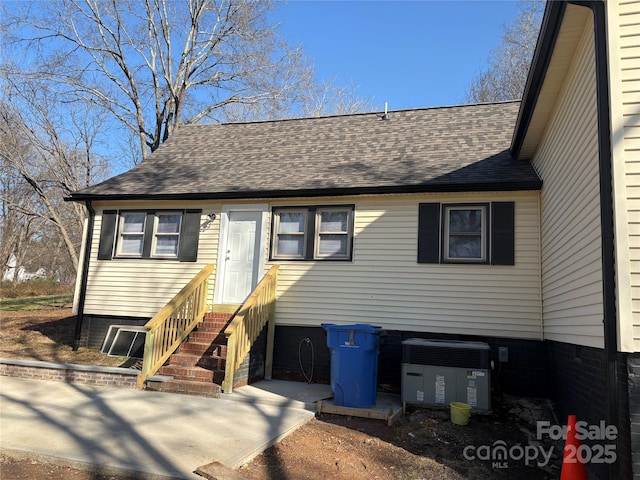 view of front of home with entry steps, roof with shingles, and central AC unit