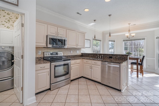 kitchen featuring hanging light fixtures, appliances with stainless steel finishes, sink, and kitchen peninsula