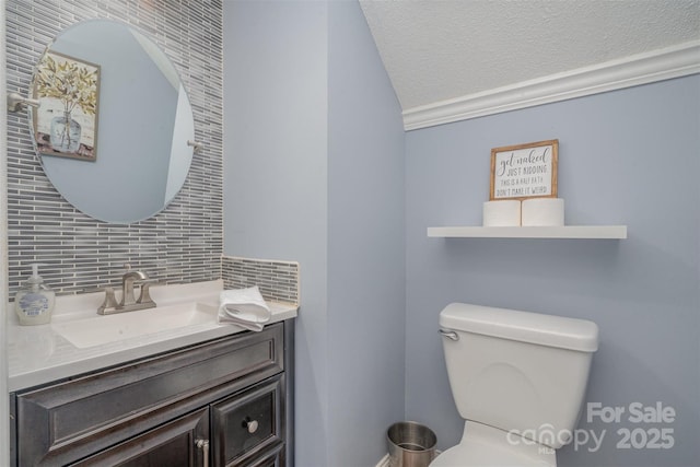 bathroom with a textured ceiling, toilet, vanity, and decorative backsplash