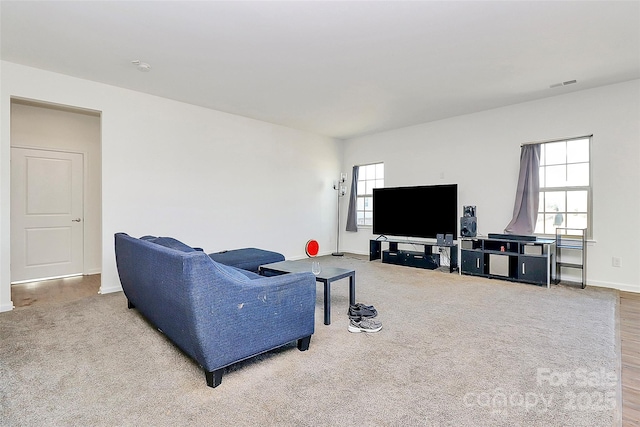 carpeted living area featuring baseboards, visible vents, and a wealth of natural light