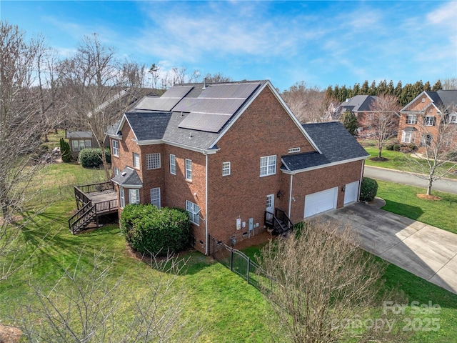 view of side of property with a lawn, solar panels, a garage, and a wooden deck