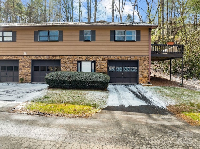 view of front of property featuring a garage, stone siding, driveway, and a deck