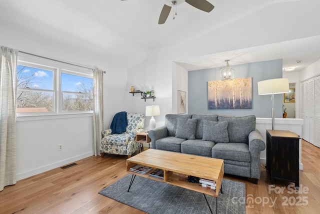 living area featuring light wood-style floors, visible vents, baseboards, and ceiling fan with notable chandelier