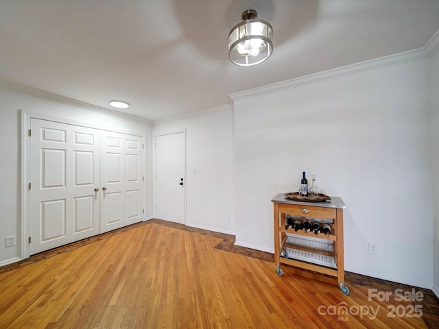 foyer featuring baseboards, ornamental molding, and light wood-style floors