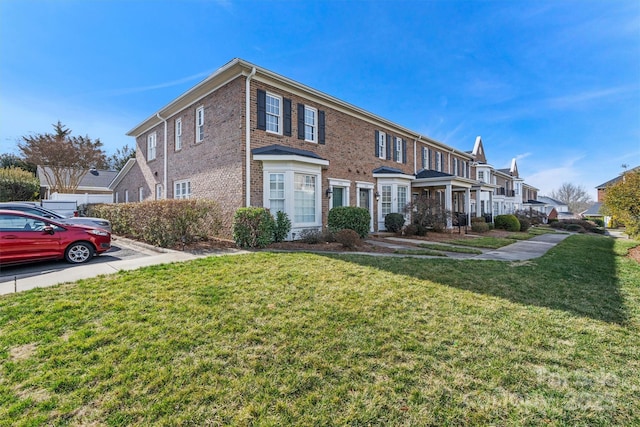 multi unit property with a residential view, brick siding, and a front lawn