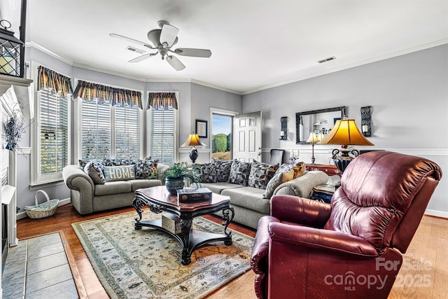 living area featuring wood finished floors, visible vents, and crown molding