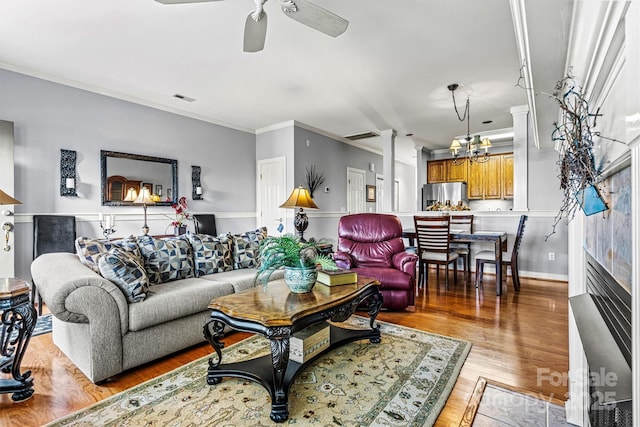 living area with light wood-type flooring, visible vents, crown molding, and ceiling fan with notable chandelier