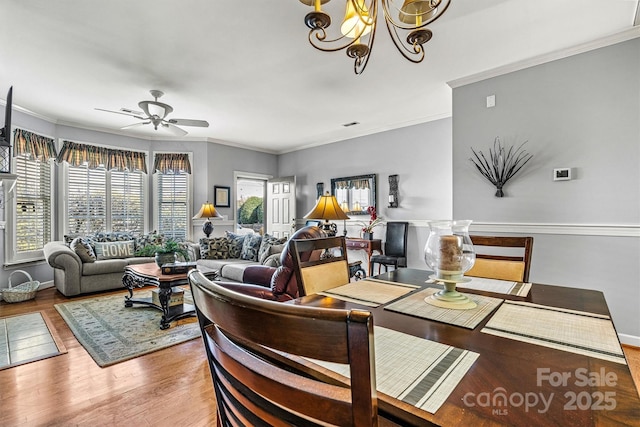 living room with crown molding, baseboards, wood finished floors, and ceiling fan with notable chandelier