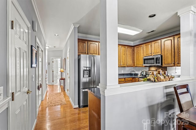 kitchen with visible vents, dark countertops, appliances with stainless steel finishes, brown cabinets, and a peninsula