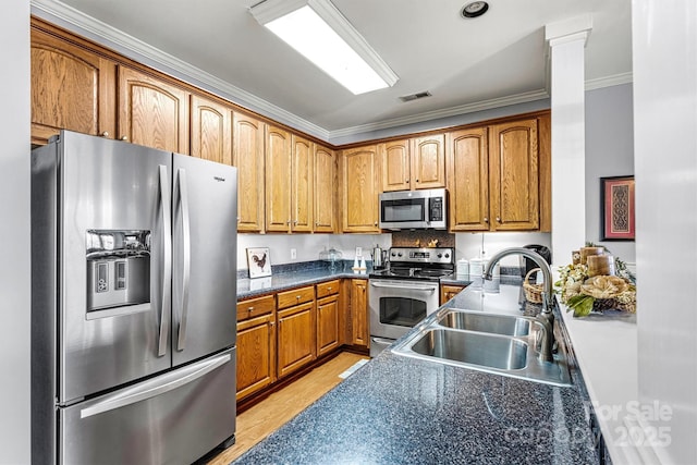 kitchen featuring dark countertops, visible vents, light wood-style flooring, appliances with stainless steel finishes, and a sink