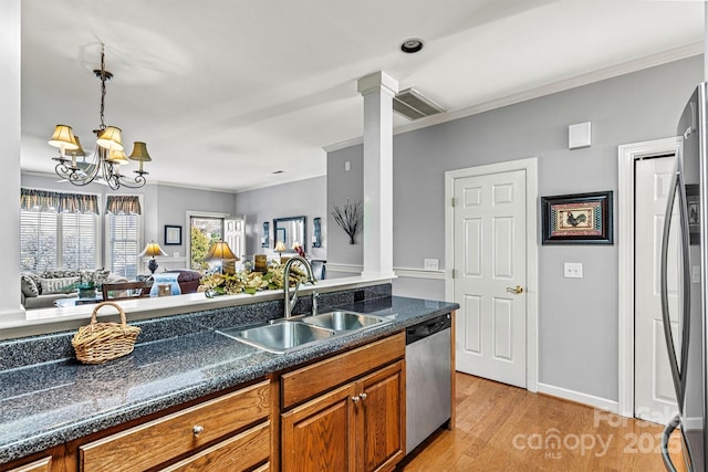 kitchen with visible vents, appliances with stainless steel finishes, brown cabinets, crown molding, and a sink