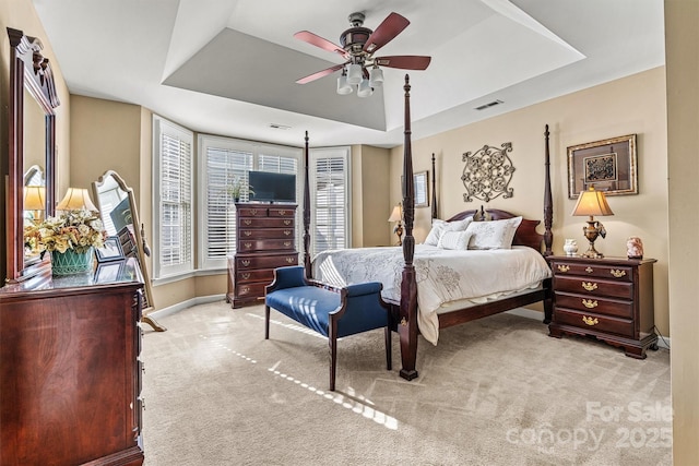 bedroom featuring light colored carpet, a tray ceiling, and visible vents