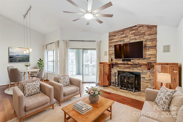 living area with lofted ceiling, light wood-type flooring, ceiling fan, and a fireplace