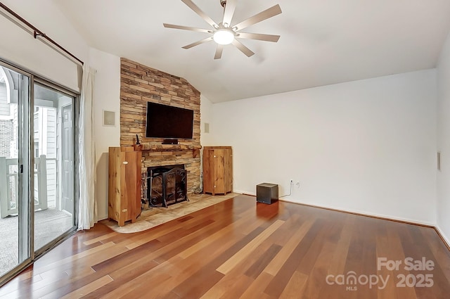 unfurnished living room with lofted ceiling, a ceiling fan, wood finished floors, and a stone fireplace