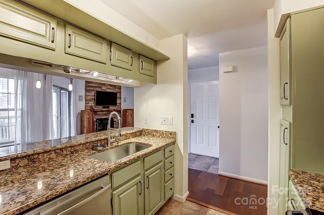 kitchen with dark stone counters, green cabinets, a sink, and dishwasher