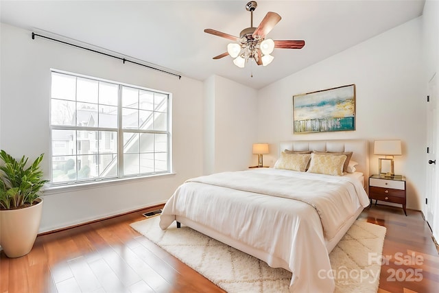 bedroom featuring lofted ceiling, wood finished floors, visible vents, and a ceiling fan