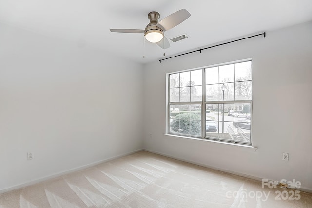 unfurnished room with a ceiling fan, visible vents, light carpet, and baseboards