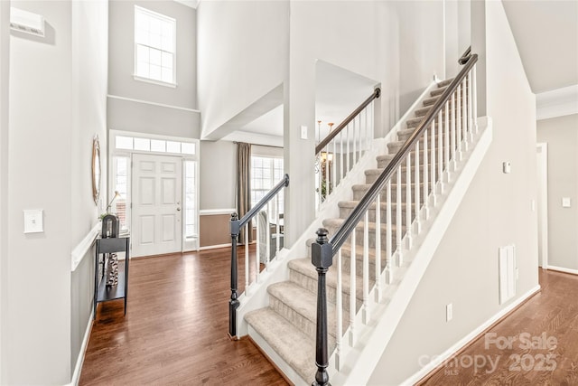 foyer featuring hardwood / wood-style flooring, crown molding, and a high ceiling