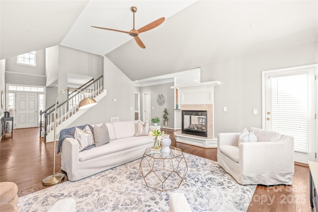 living room with high vaulted ceiling, wood-type flooring, a multi sided fireplace, and ceiling fan