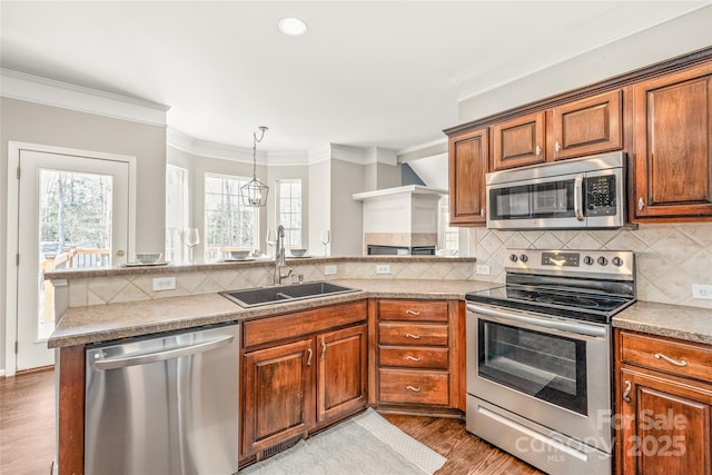 kitchen with kitchen peninsula, light hardwood / wood-style flooring, stainless steel appliances, crown molding, and sink