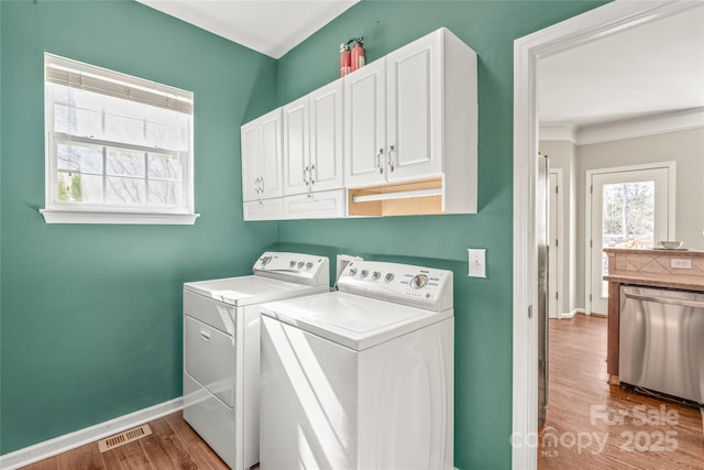 laundry room featuring light wood-type flooring, cabinets, and washer and dryer