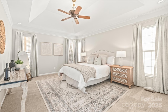 bedroom featuring light colored carpet, ceiling fan, a tray ceiling, and ornamental molding