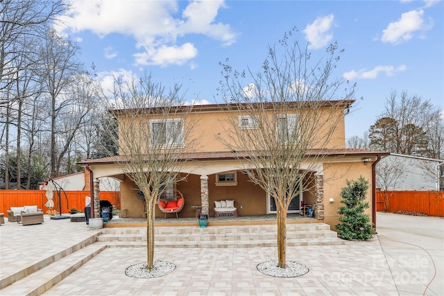 exterior space with a patio area, fence, an outdoor living space, and stucco siding