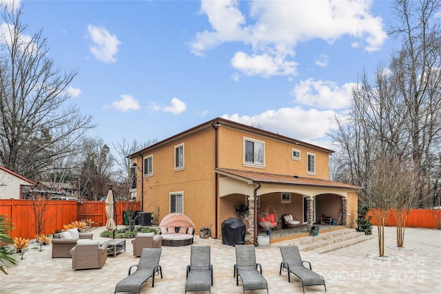 back of property featuring a fenced backyard, a patio, an outdoor hangout area, and stucco siding