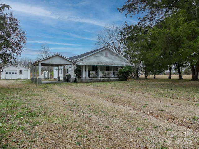 ranch-style house with an outbuilding, a garage, a front lawn, and a porch