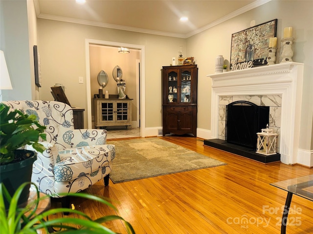 sitting room with a fireplace, crown molding, and wood-type flooring